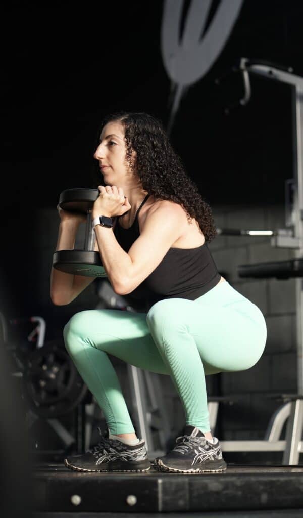 brittany doing a goblet squat while holding a dumbbell up by her chest