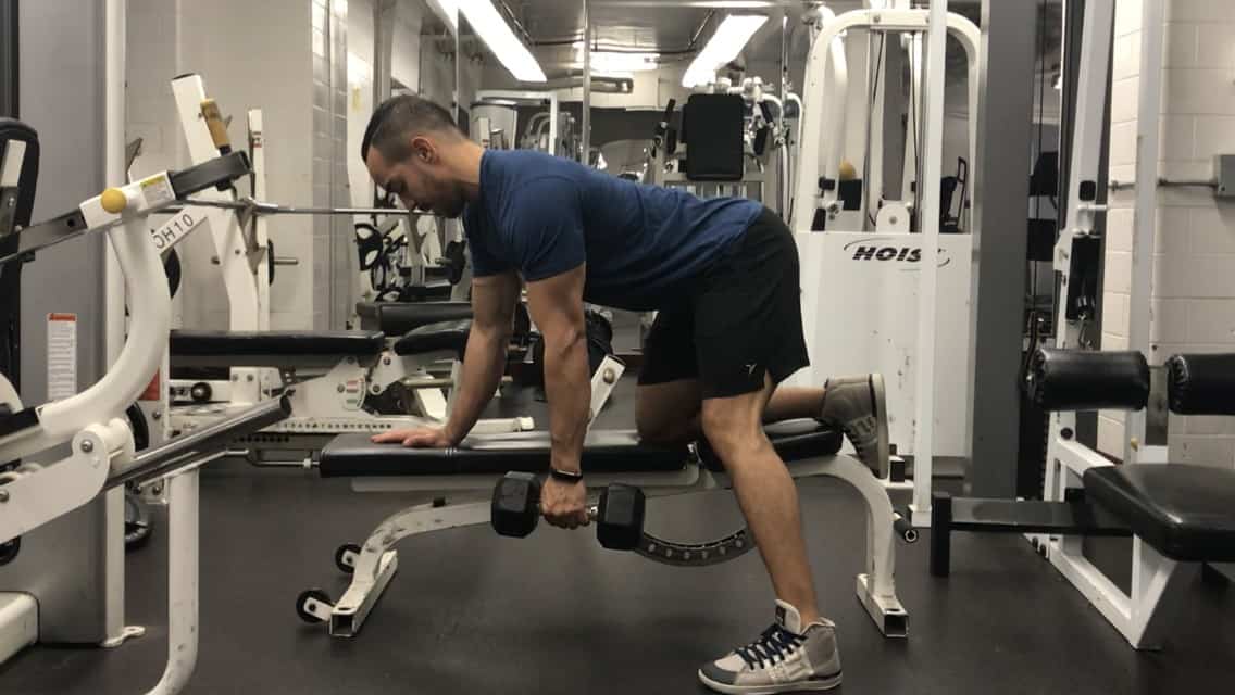 single-arm-dumbbell-row-form- alex kneeling on bench with one knee with a flat back holding a dumbbell in his outstretched arm