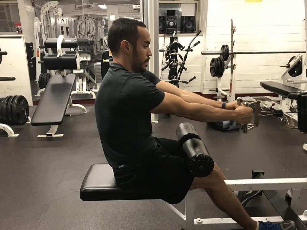 alex on a seated cable row machine showing bad posture with a rounded spine