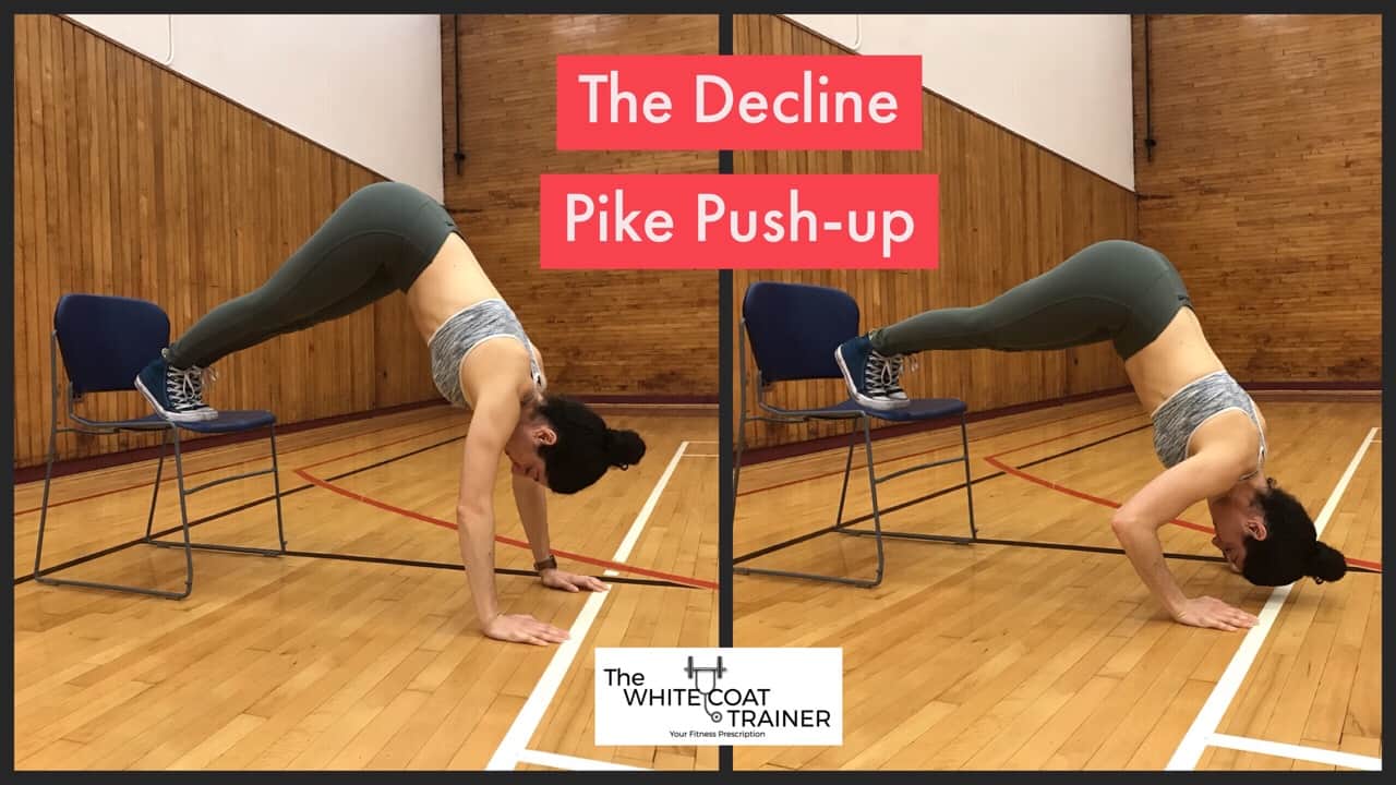decline-pike-pushup-exercise: Brittany with her hands on the floor, feet elevated on a chair, with her butt up toward the sky, bringing the crown of her head to the floor by bending her elbows