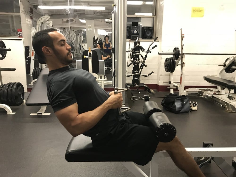 alex on a seated cable row machine showing bad posture by leaning back excessively as he pulls the weight toward his abdomen