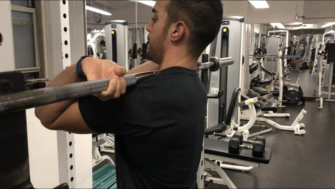 alex showing the standard front squat grip resting the barbell on the anterior shoulders with his elbows high and palms facing up