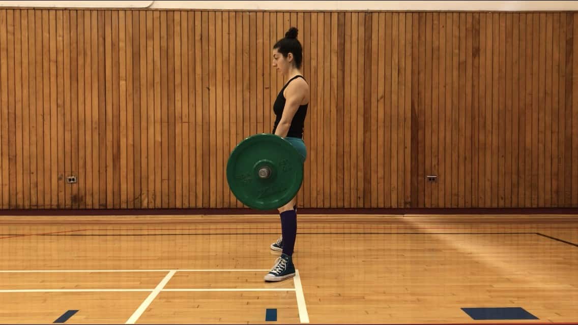 brittany at the top of the sumo deadlift, standing upright with the barbell in her outstretched hands and in contact with her thighs