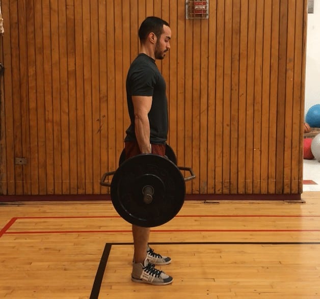 trap bar deadlift top position: standing up tall with the bar in his outstretched arms