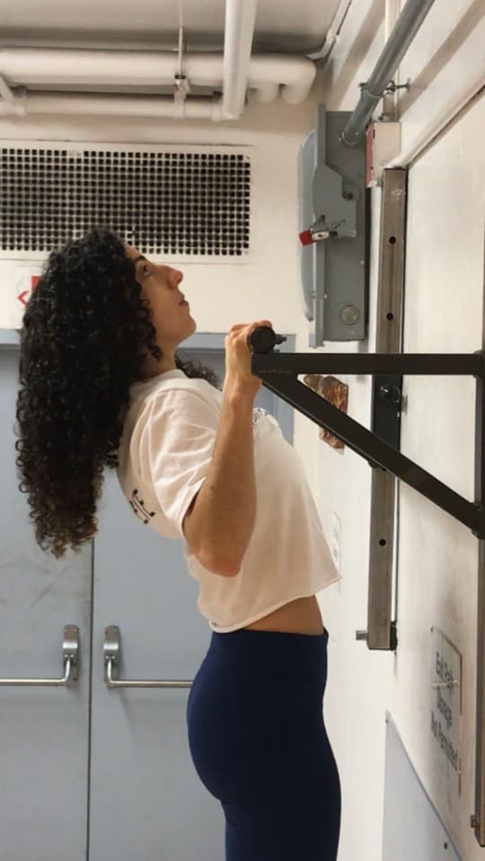 brittany at the top of a pullup side view: bringing her chest to the bar and her chin is naturally above the bar