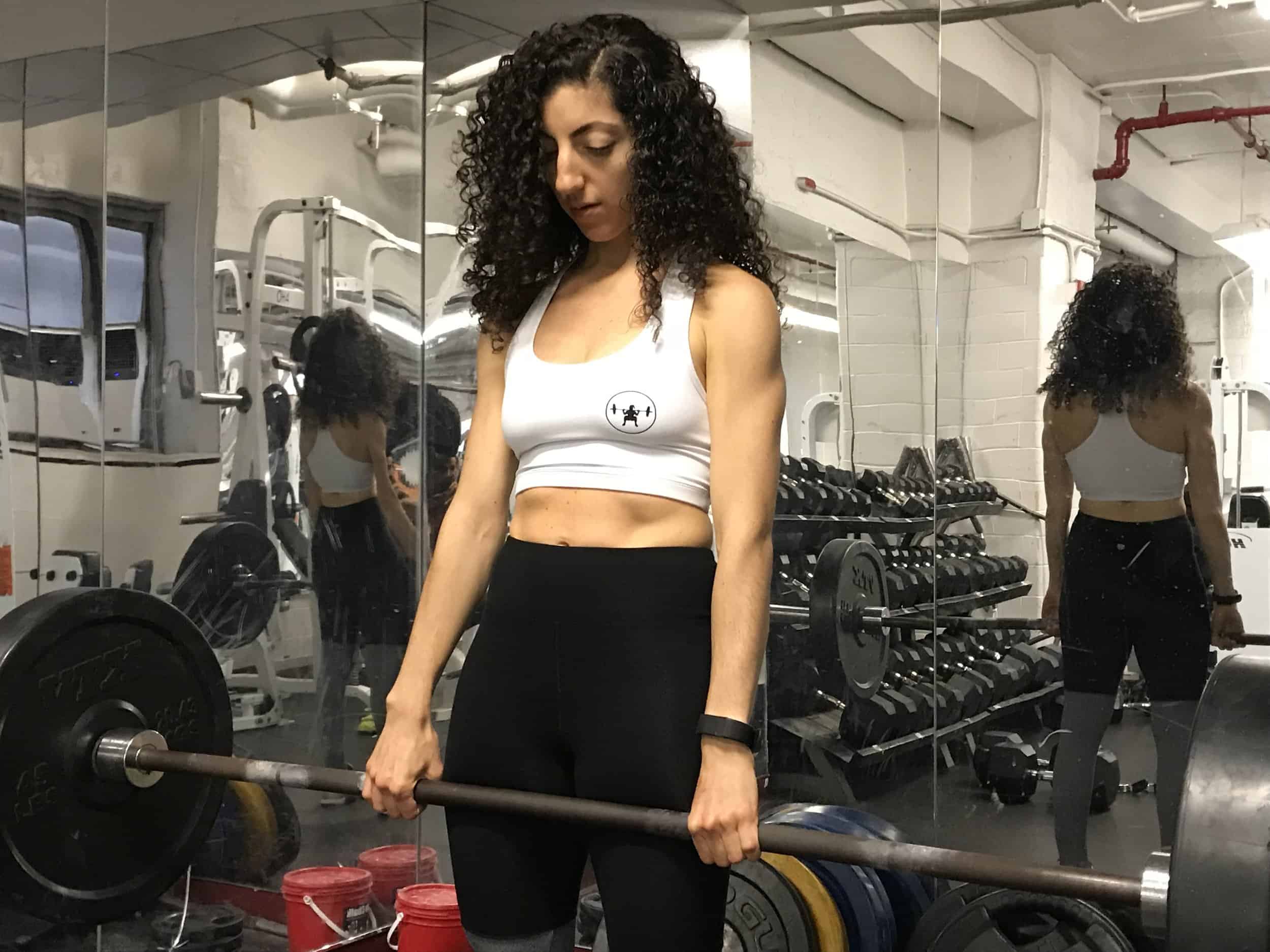 brittany-doing-deadlift-holding a barbell close to her thighs