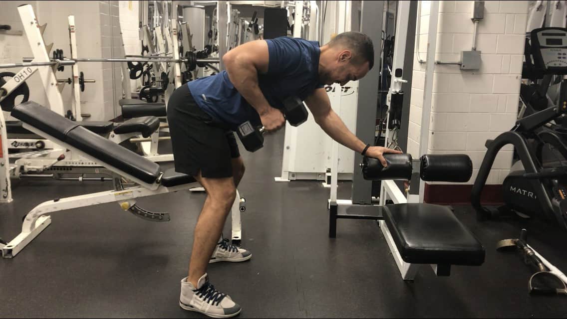 showing the dumbbell row while standing and maintaining a bent over position