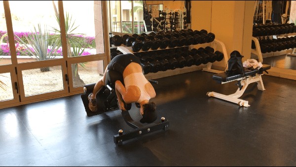 brittany at the bottom of a back raise, flexing her torso down toward her feet on a back raise machine