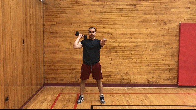 alex standing tall with one dumbbell resting on his right shoulder