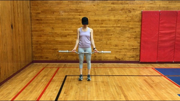 brittany standing up tall holding the ez bar in her outstretched hands