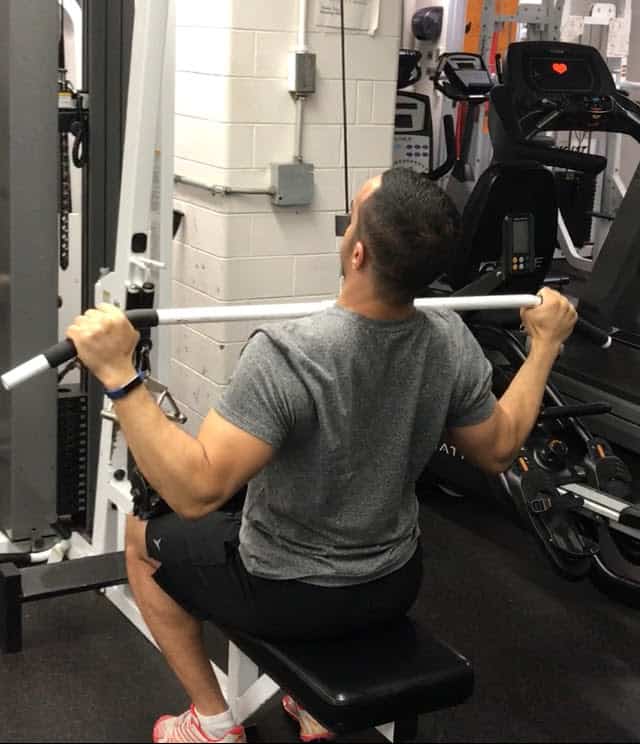alex at the bottom of a lat pulldown with the bar at his clavicles, upper back arched, and elbows in close to his body