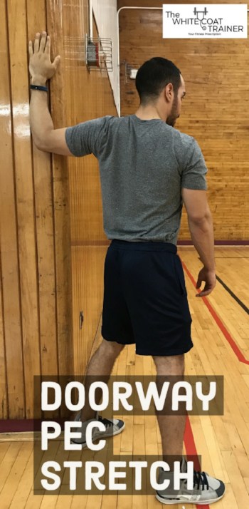 alex stretching his chest muscle by holding his arm on a corner of a wall