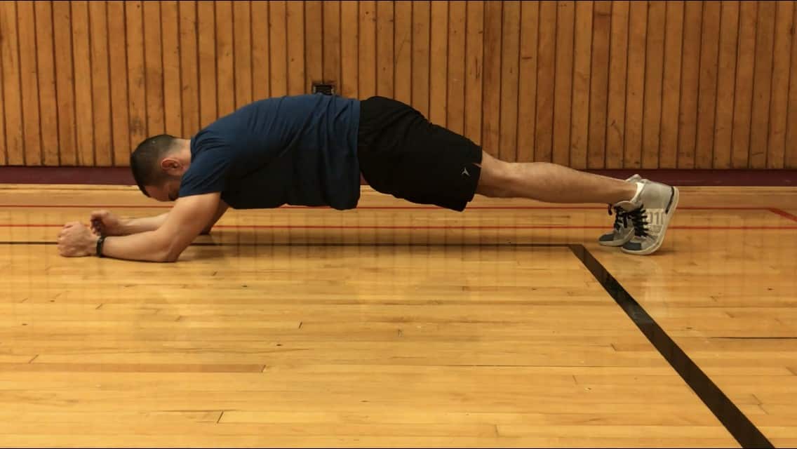 alex showing posterior pelvic tilt while in a plank position (lower back is neutral and upper back is slightly rounded)