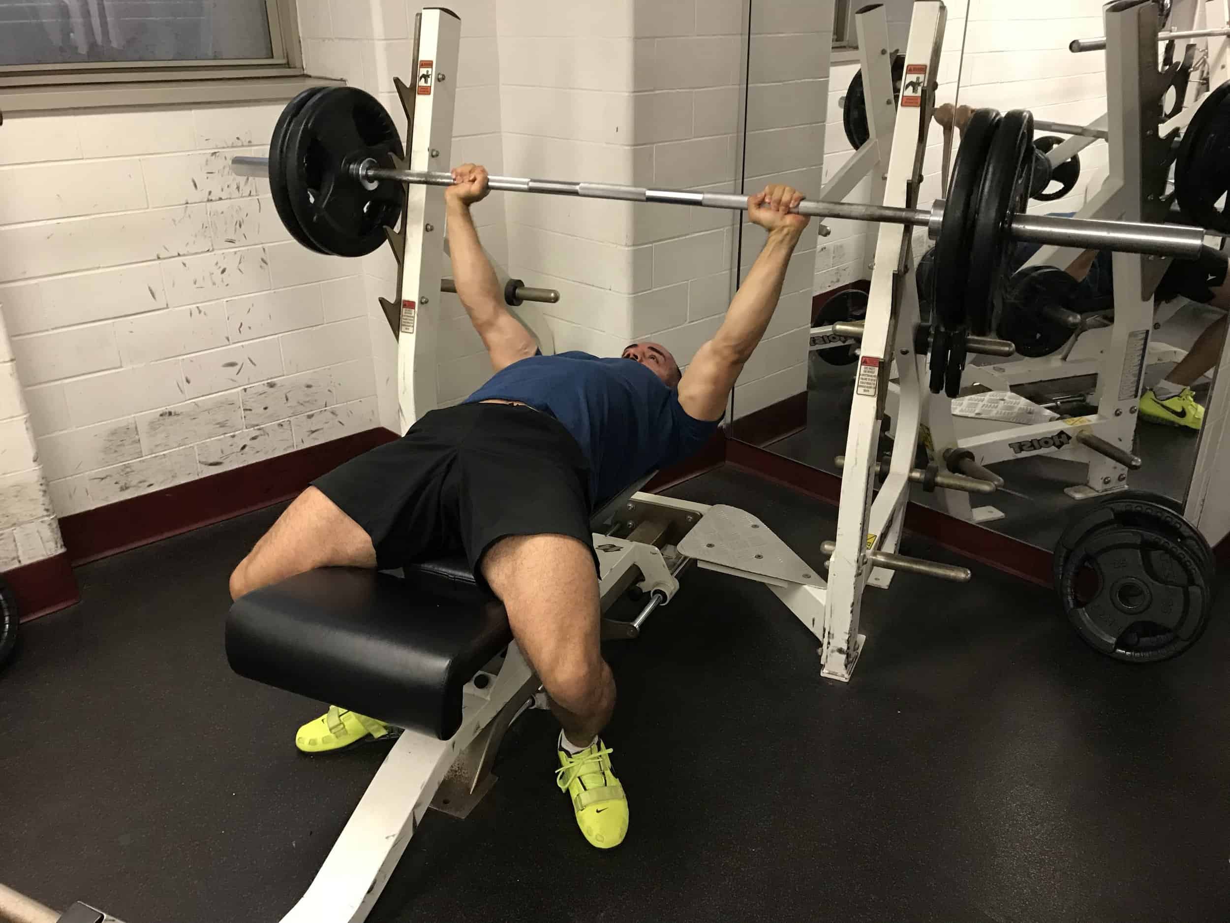 alex on a bench press with the barbell in his extended arms