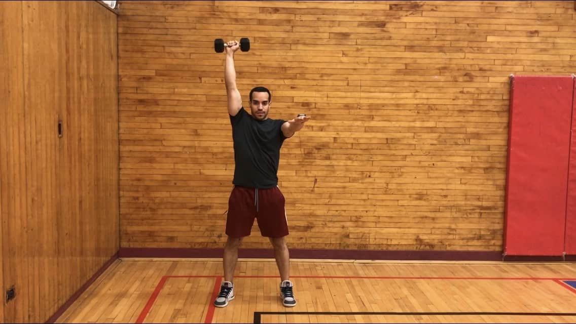 alex standing tall with one dumbbell pressed up overhead 