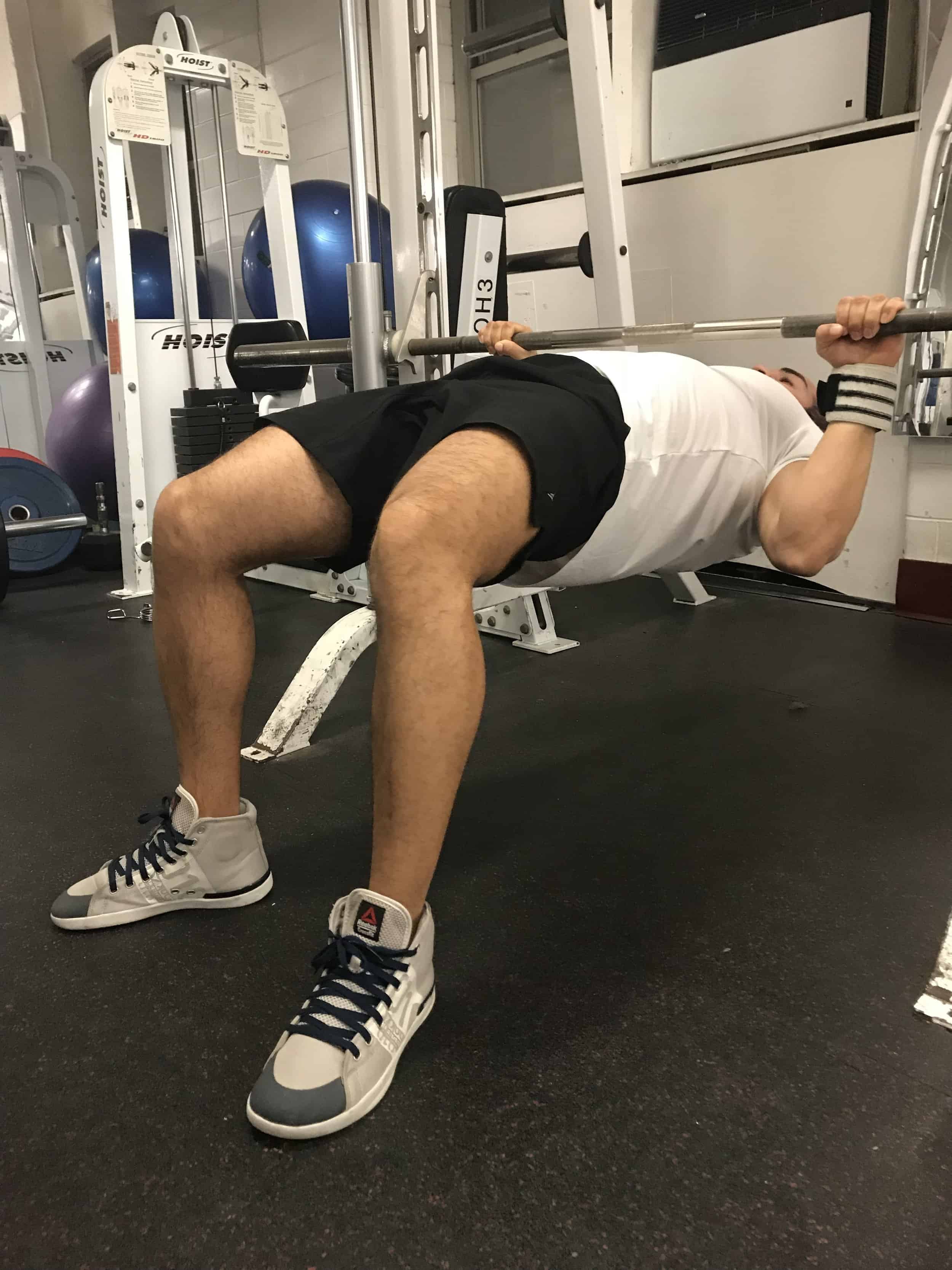 alex doing horizontal pullup hanging from a barbell with his knees bent and body parallel to the ground