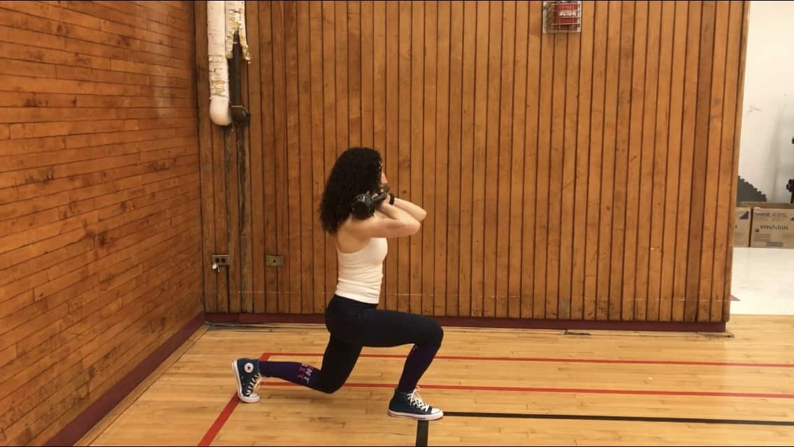 brittany lunging down with her front knee at a 90-degree angle to the floor and holding weights up on her shoulders