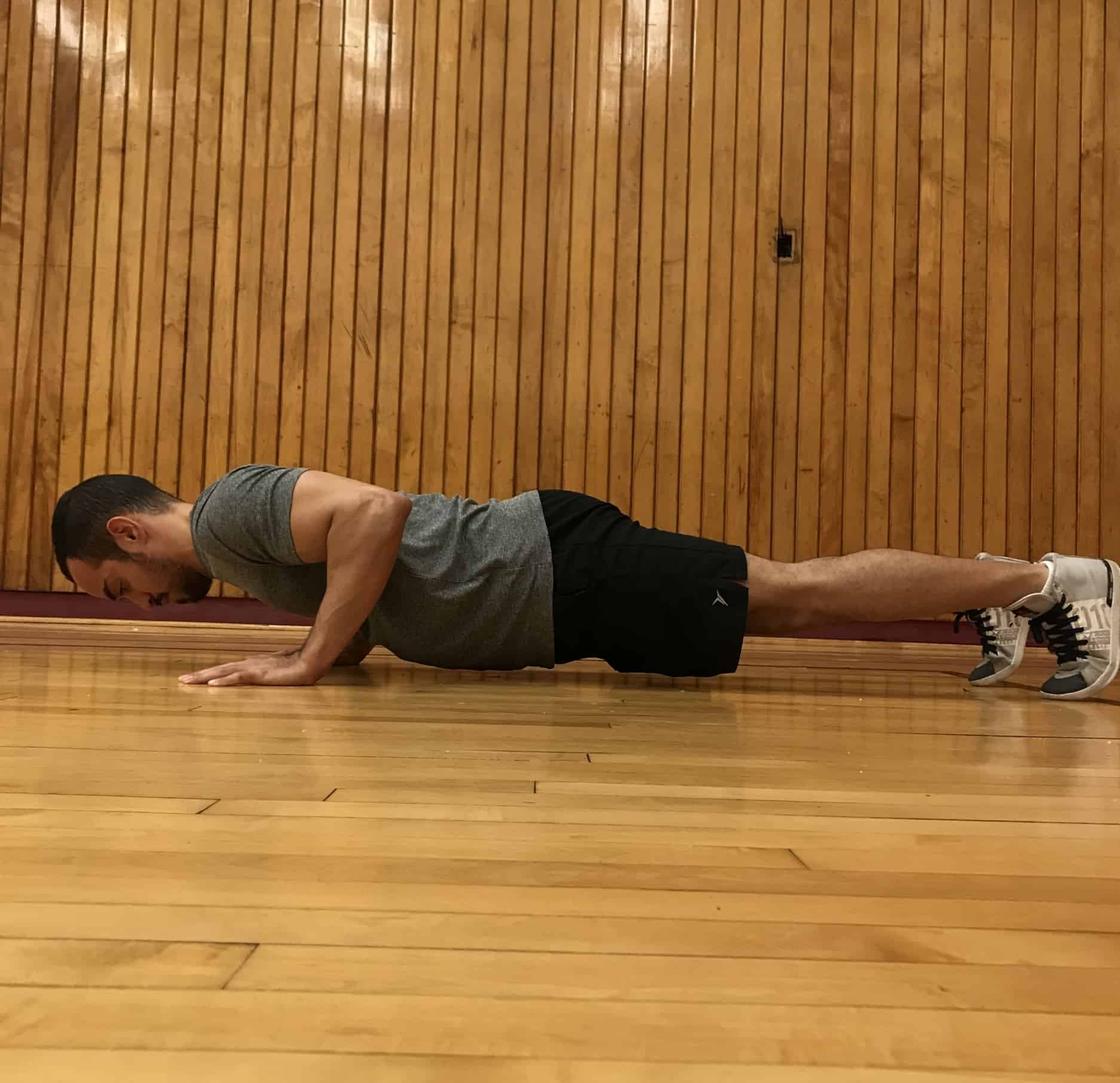 alex in the bottom pushup position with his elbows bent head neutral and spine flat 