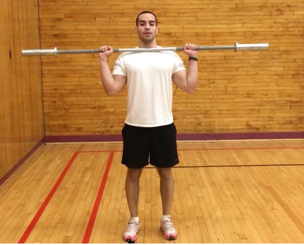 alex holding a barbell up on his shoulders while standing- front view