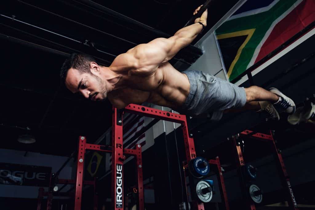 alex doing a back level, hanging from a bar with his chest facing the floor and his body completely horizontal
